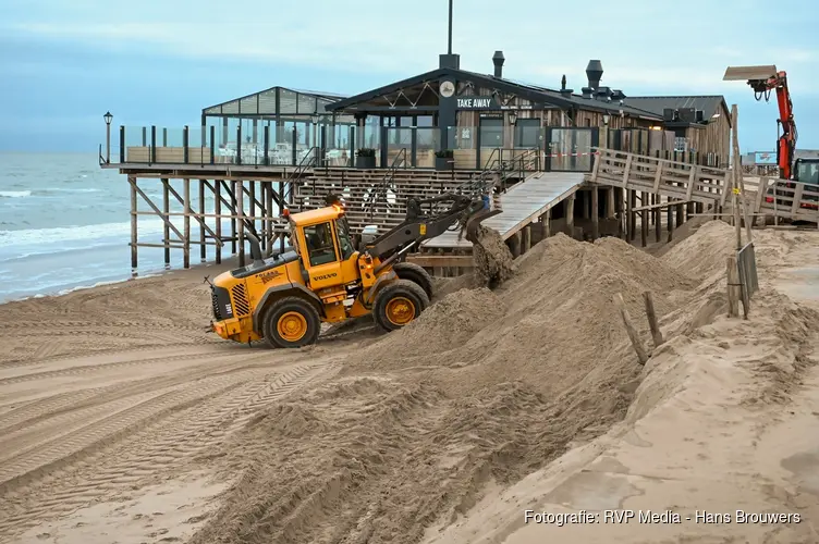 Trekkers en shovels aan het werk om weggeslagen zand te herstellen