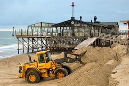 Trekkers en shovels aan het werk om weggeslagen zand te herstellen