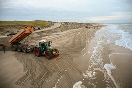 Trekkers en shovels aan het werk om weggeslagen zand te herstellen